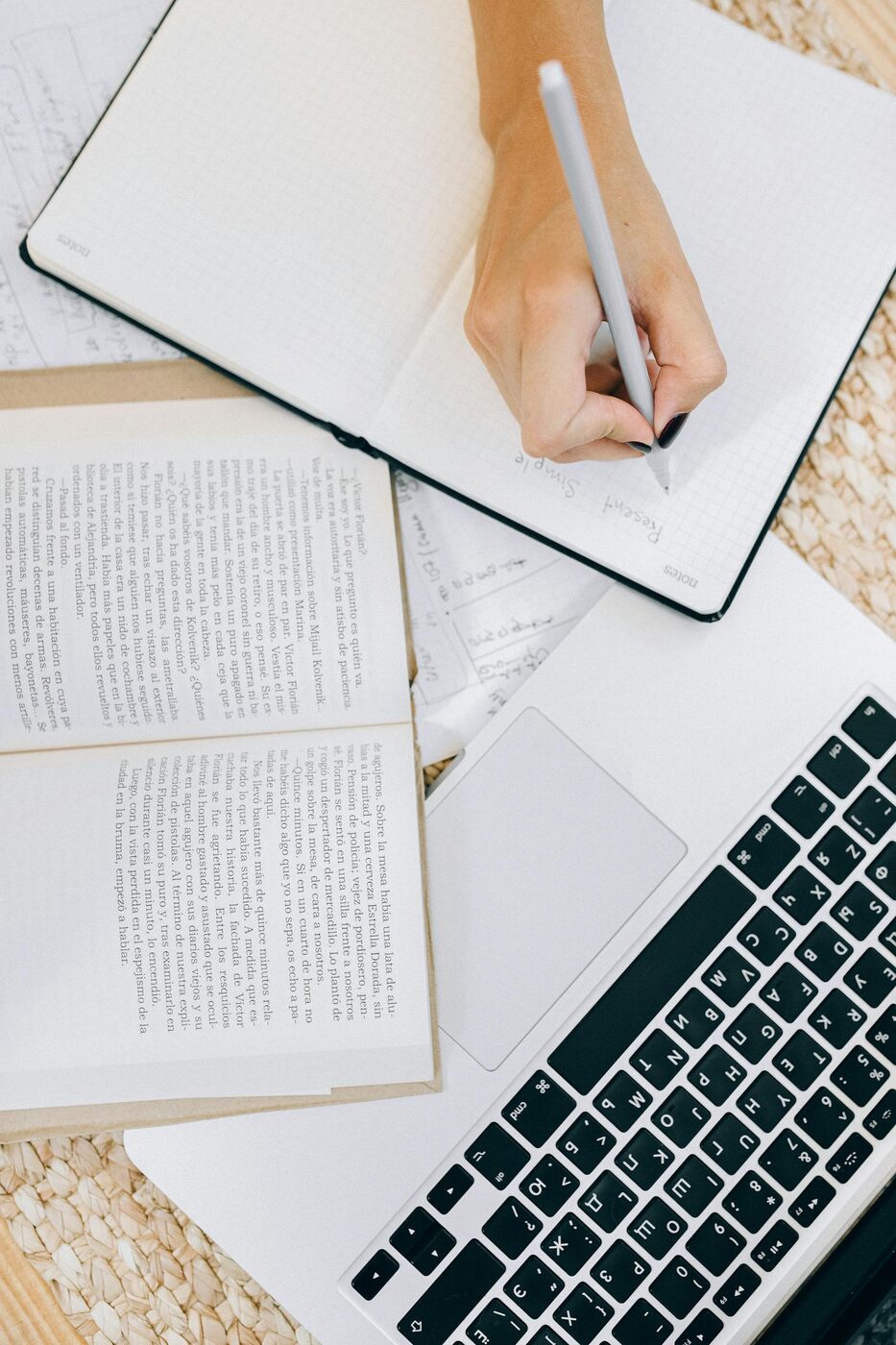 A woman writing in an open notebook at her desk — planning as an ongoing, adaptive practice.